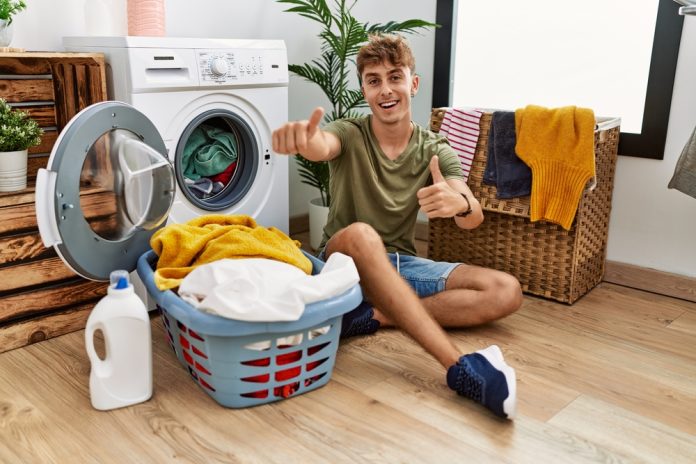 Young,Caucasian,Man,Putting,Dirty,Laundry,Into,Washing,Machine,Approving