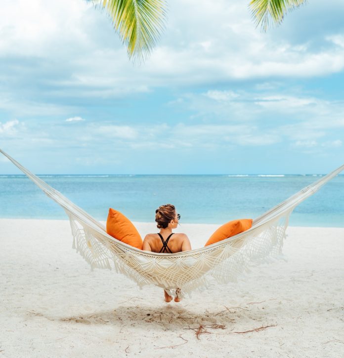 Young,Woman,Relaxing,In,Wicker,Hammock,On,The,Sandy,Beach