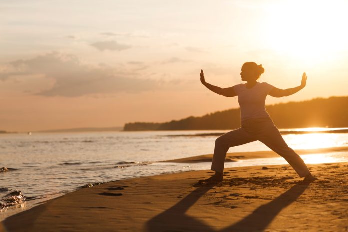 Woman,Praticing,Tai,Chi,Chuan,At,Sunset,On,The,Beach.