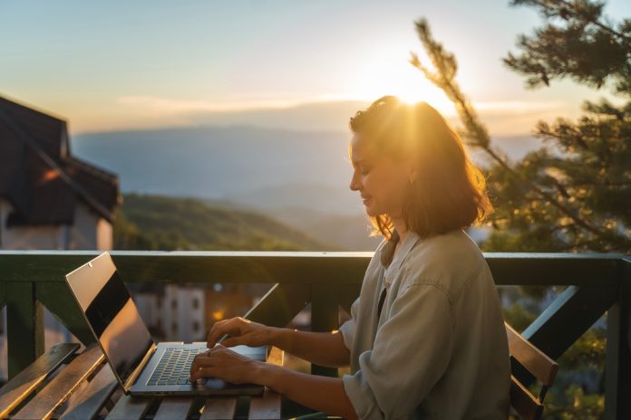 Young,Woman,Sitting,On,Balcony,With,View,Of,Mountains,And