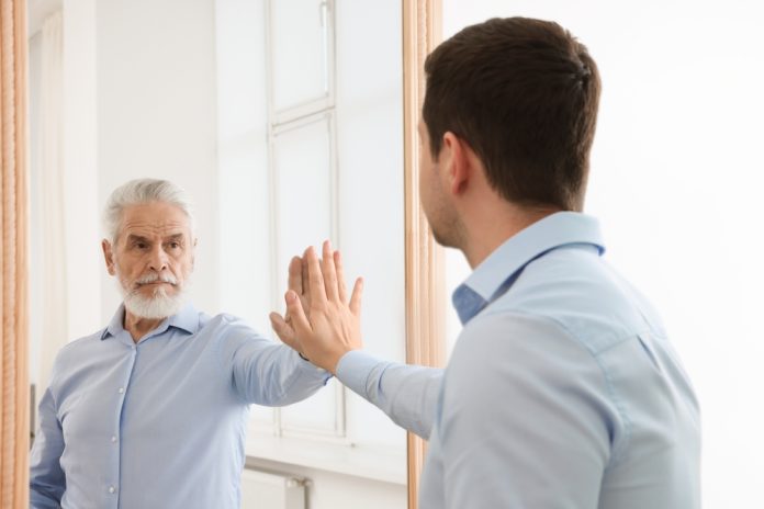 Young,Man,Seeing,Himself,In,Mirror,As,Senior,Man.,Concept