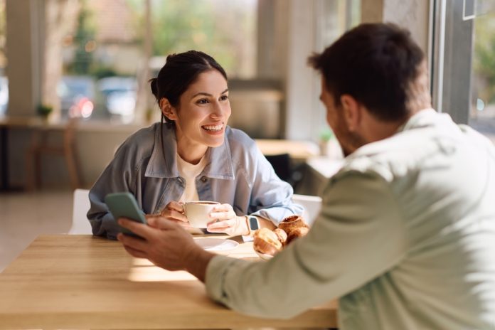 Happy,Woman,Talking,To,Her,Boyfriend,While,Having,Cup,Of