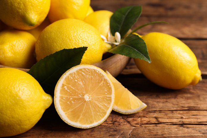 Many,Fresh,Ripe,Lemons,With,Green,Leaves,On,Wooden,Table,