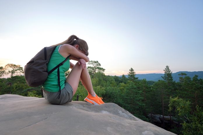 Lonely,Sad,Hiker,Woman,Sitting,Alone,On,Rocky,Mountain,Top