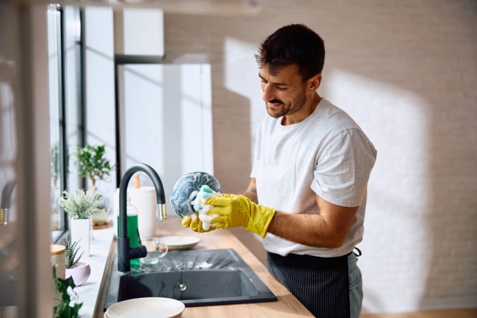 Young,Smiling,Man,Doing,Dishes,In,The,Kitchen.,Copy,Space.
