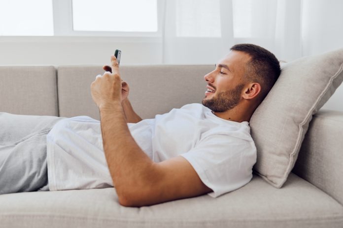 Relaxed,Man,Engaging,With,Technology,While,Lounging,On,A,Couch,