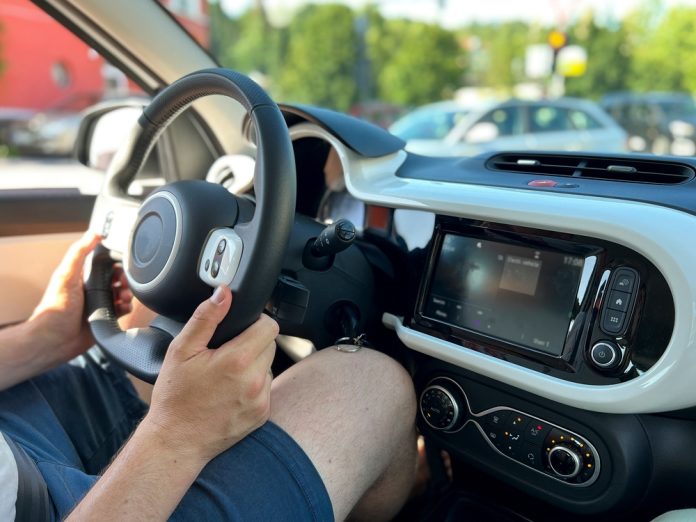 Tall,Man,Driving,A,Small,Electric,Car,,Knees,Resting,On