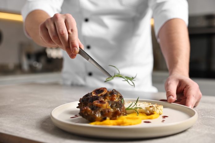 Professional,Chef,Serving,Dish,At,Table,Indoors,,Closeup