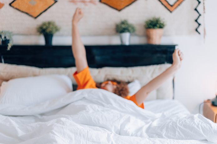 A,Relaxed,Woman,Stretches,Her,Arms,In,Bed,After,Waking