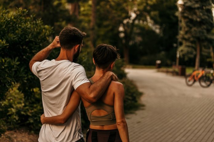 Couple,Walking,Together,In,Park,After,Exercising,,Man,Embracing,Woman