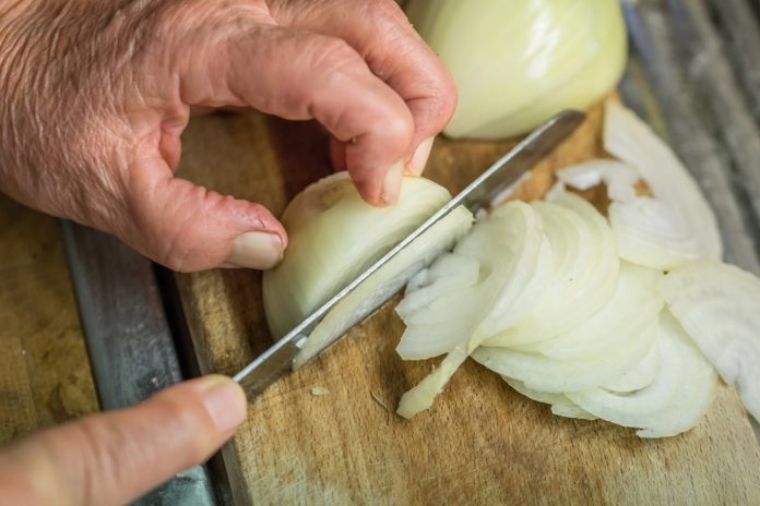 Old,Woman,Granny,Cutting,Onion,In,Kitchen,With,Knife,And