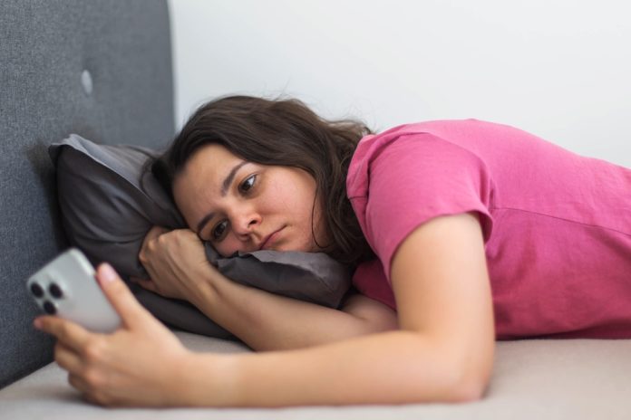 A,Woman,Lies,In,Bed,Staring,At,Her,Phone,With